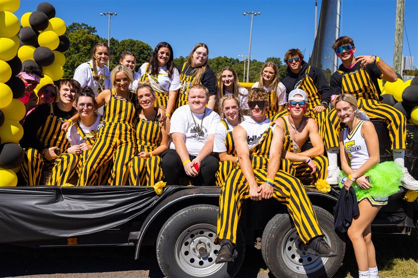 Students ride on a float during a homecoming parade